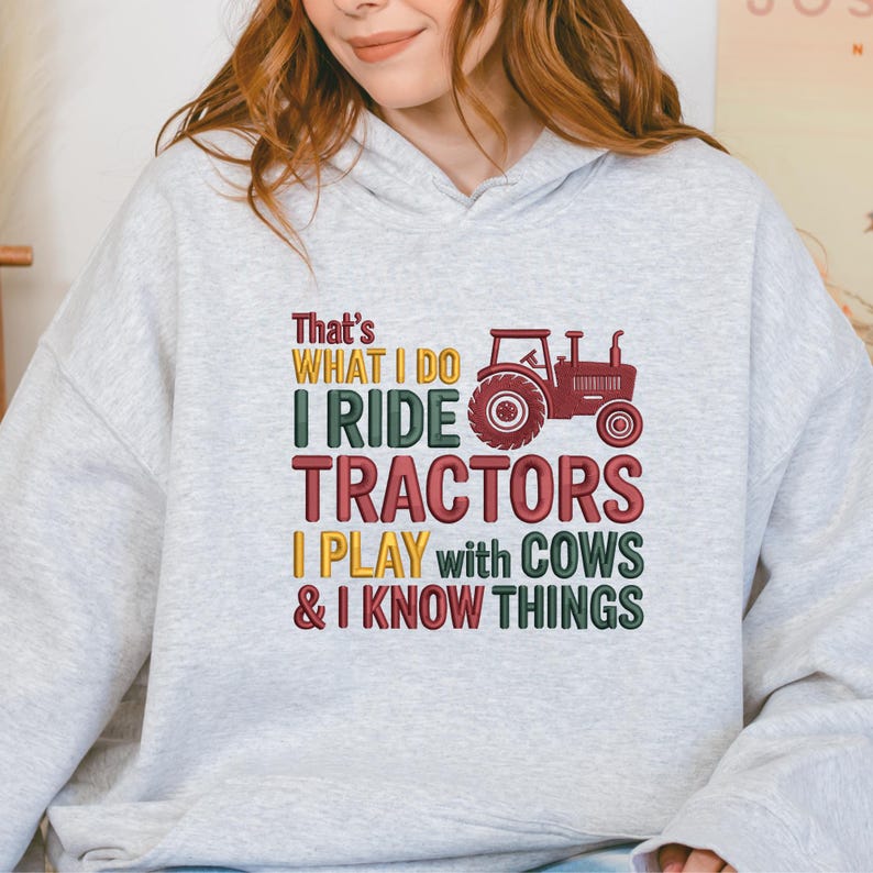 Peut inclure: Un sweat-shirt gris clair avec l'inscription "That's What I Do, I Ride Tractors, I Play with Cows & I Know Things." Le motif comprend un tracteur rouge. Le texte est de couleurs vari&eacute;es.