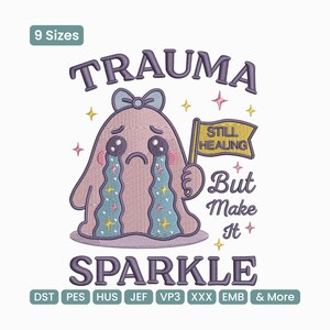 Puede incluir: Un diseño bordado con un fantasma llorando con el texto "TRAUMA" arriba y "SPARKLE" abajo. El fantasma sostiene una bandera que dice "STILL HEALING But Make It". El diseño incluye estrellas y un lazo.
