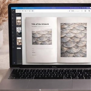 Pu&ograve; includere: Un computer portatile argentato che mostra un documento digitale sullo schermo. Il documento presenta un layout con il testo Title of the Artwork, The Visuals e immagini di squame circolari sovrapposte. Il portatile ha una tastiera nera e telaio.