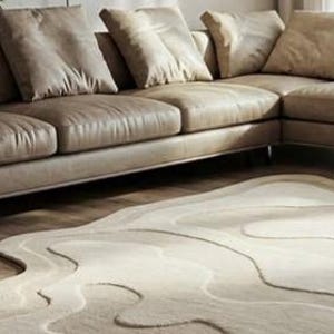 Pu&ograve; includere: Un moderno divano angolare in pelle marrone chiaro con diversi cuscini coordinati. Un tappeto beige con un design unico e fluido &egrave; posto di fronte al divano, creando un'atmosfera accogliente nel soggiorno.