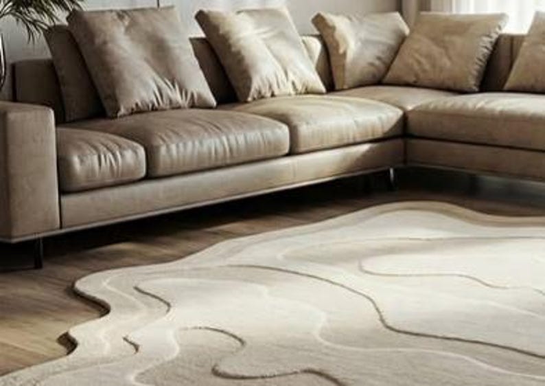 Pu&ograve; includere: Un moderno divano angolare in pelle marrone chiaro con diversi cuscini coordinati. Un tappeto beige con un design unico e fluido &egrave; posto di fronte al divano, creando un'atmosfera accogliente nel soggiorno.
