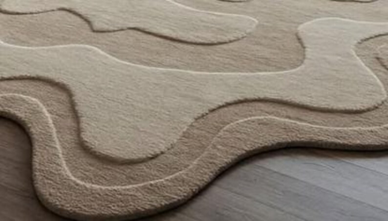 Pu&ograve; includere: Un tappeto beige con un design organico a strati. Il tappeto presenta diverse tonalit&agrave; di beige e marrone chiaro, creando un effetto strutturato e tridimensionale. I bordi del tappeto hanno una forma morbida e fluida, che contribuisce alla sua estetica moderna.