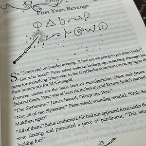 May include: Open book page with text, chapter title "First Year: Revenge", and a drawing of a wand emitting light. The page also features a drawing of a broom and the number 33.