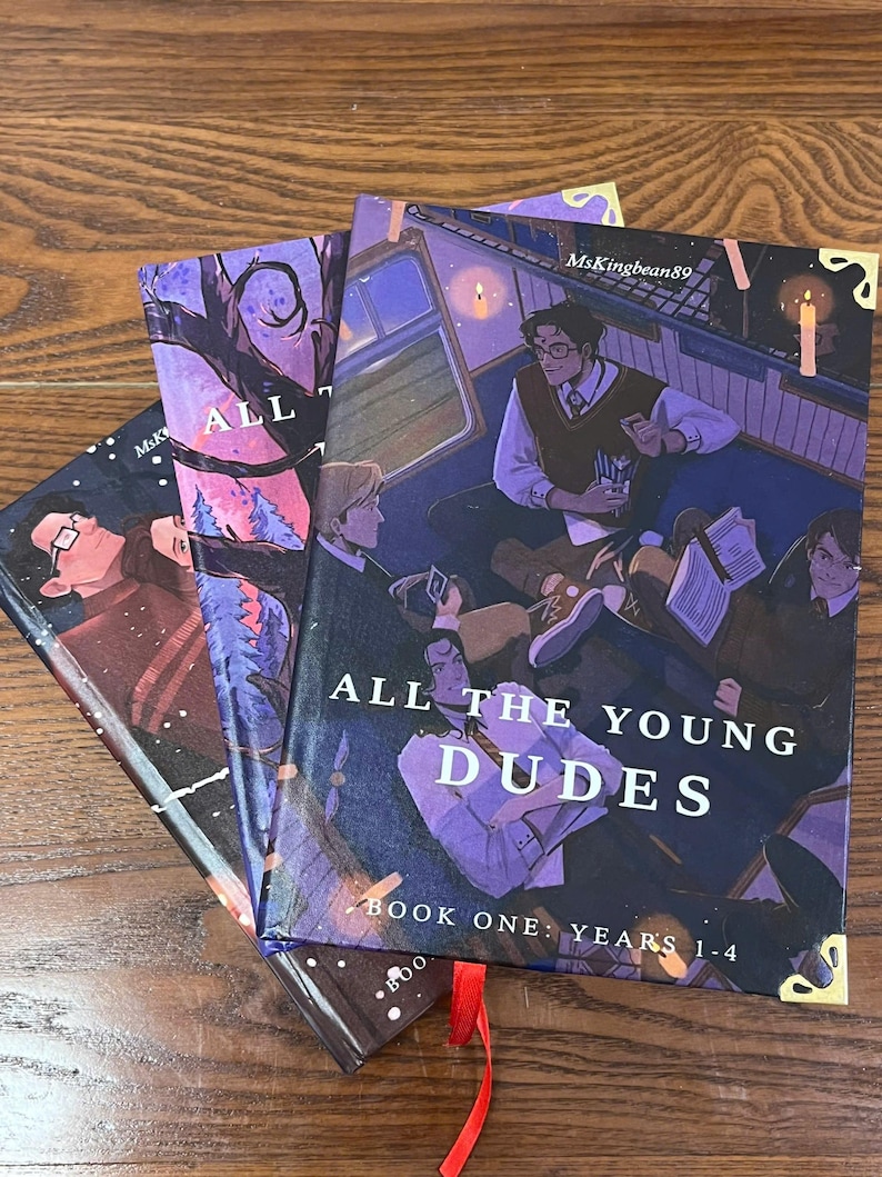 May include: Three hardcover books with illustrated covers. The book covers feature illustrations of young people in a train car, with the title "ALL THE YOUNG DUDES" and "BOOK ONE: YEARS 1-4". A red ribbon bookmark is visible.
