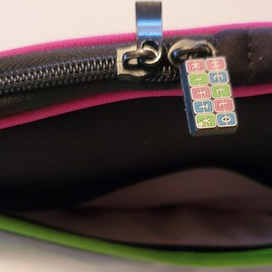 Pu&ograve; includere: Una custodia per laptop rosa e verde con una cerniera nera e un tiretto della cerniera colorato con il testo "EGGO" su di essa.