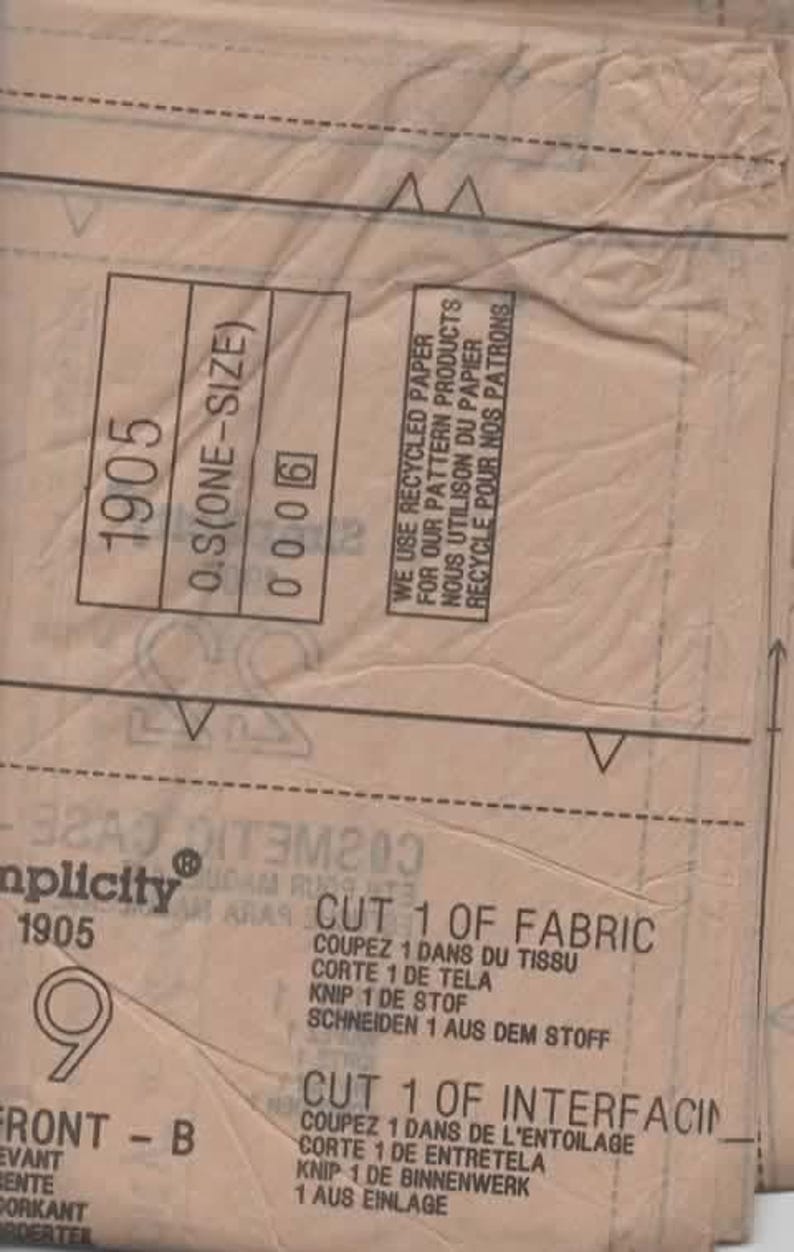 May include: A close-up of a tan sewing pattern with the number 1905 and the text "O.S (ONE-SIZE)". The pattern includes instructions in multiple languages, including English and French. The text "WE USE RECYCLED PAPER" is also visible.