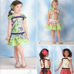 May include: Simplicity sewing pattern number 1627A for girls' dresses. The pattern includes three different styles: a green floral dress with ruffles, a pink floral dress with ruffles, and a red and white gingham dress with a black bow.
