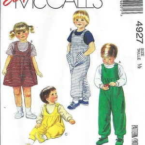 May include: McCall's sewing pattern 4927 for children's clothing. The pattern features illustrations of a dress, overalls, and a jumpsuit. The clothing items are in red, yellow, and green. The text "Easy McCall's" is at the top.