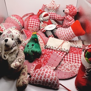 May include: A collection of Christmas-themed plush decorations. Includes red and white gingham and floral patterned ornaments, stockings with "HO HO HO" text, a green tree, and teddy bears. A sock monkey toy is also present.
