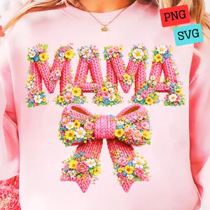 May include: A light pink sweatshirt featuring the word "MAMA" in a knitted style, adorned with colorful floral arrangements. A matching pink bow with floral accents is below the text. The design includes yellow, blue, and white flowers.