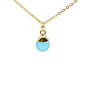 May include: A delicate gold-colored necklace with a small, light blue teardrop pendant. The pendant has a gold-colored cap. The necklace is displayed against a white background.