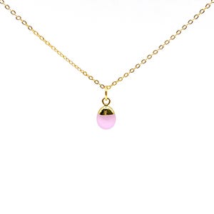 May include: A delicate gold necklace featuring a small, teardrop-shaped pendant. The pendant is a soft pink color with a gold-colored cap. The chain and pendant hardware are also gold. The necklace is displayed against a white background.