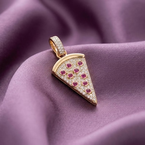 Può includere: Un ciondolo in oro a forma di fetta di pizza, caratterizzato da un pavé di pietre bianche trasparenti sulla superficie e diverse pietre rotonde rosa acceso incastonate come condimento, completo di una piccola contromaglia con pietre.