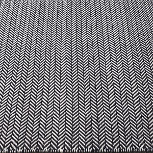 May include: A rectangular area rug featuring a high-contrast black and white herringbone pattern. The woven textile displays a repeating V-shaped chevron design that runs consistently across the entire surface of the floor covering.