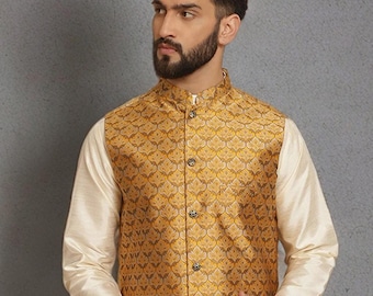 May include: A gold-colored, patterned vest with a mandarin collar and button closure. The vest is worn over a cream-colored long-sleeved shirt and paired with matching pants. The outfit is suitable for formal occasions.