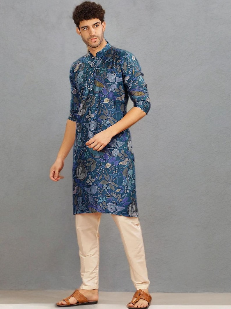 May include: A teal kurta with a floral pattern, paired with cream-colored pants. The kurta features a mandarin collar and button-down front. The outfit is completed with brown leather sandals. The overall style is a blend of traditional and contemporary fashion.