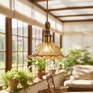 May include: A pendant light fixture featuring a scalloped, amber-tinted glass shade with a fluted petal design. The lamp includes a brass-toned metal socket housing and a dark, wood-grain textured cylindrical top piece suspended by a cord.