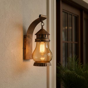 Może przedstawiać: Brązowa zewnętrzna lampa ścienna z zakrzywionym ramieniem i szklanym kloszem. Lampa ma styl vintage z ciepłą poświatą z odsłoniętej żarówki. Oprawa jest zamontowana na teksturowanej ścianie.