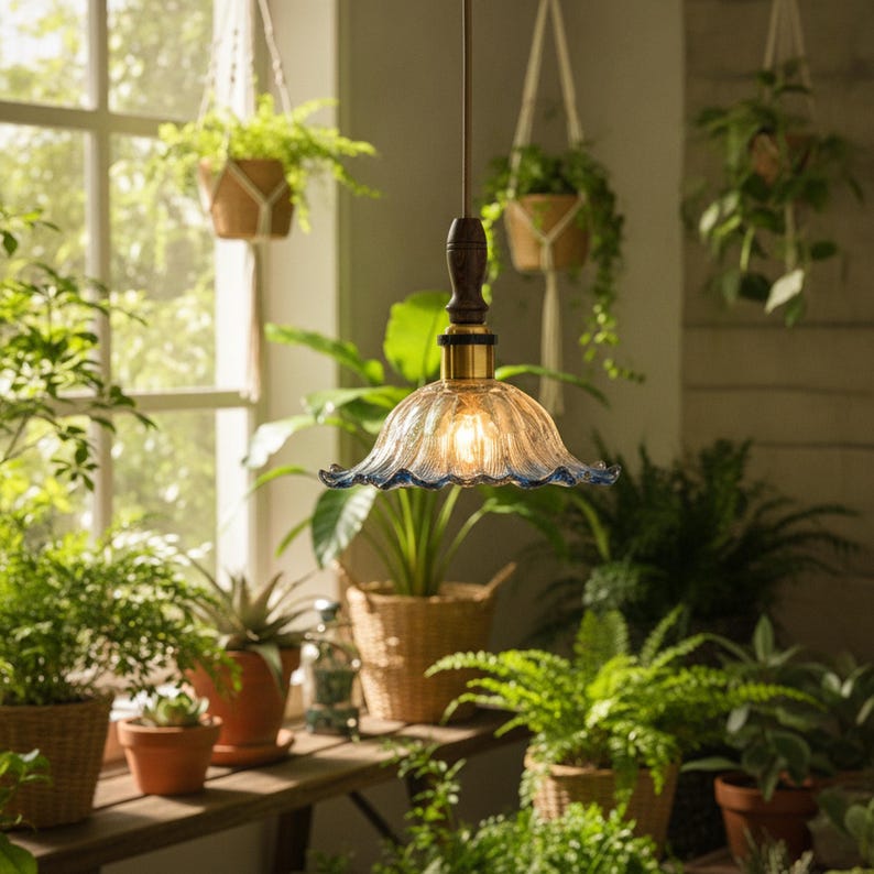 May include: A hanging pendant light featuring a clear, fluted glass shade with a delicate blue-tinted scalloped edge. The fixture includes a dark brown wooden neck, a brass-toned metal connector, and a thin cord for ceiling suspension.