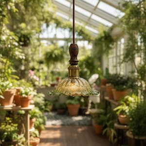 May include: A pendant light fixture featuring a fluted, translucent green glass shade shaped like a flower petal. The shade is attached to a dark brown wooden handle and a brass-colored metal socket, suspended by a thin, dark brown cord.