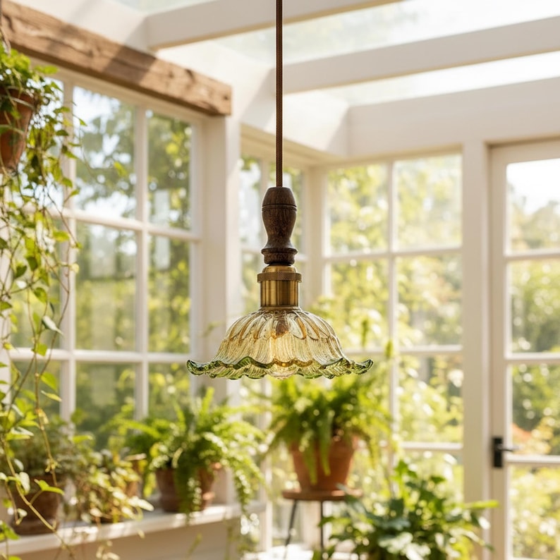May include: A pendant light fixture featuring a fluted, scalloped-edge green glass shade with a brass-toned metal socket and a dark brown wooden accent piece, suspended from a thin, straight metal rod extending upward from the fixture.