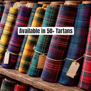 Può includere: Una collezione di rotoli di tessuto tartan in vari colori, tra cui rosso, blu, verde e giallo. Ogni rotolo è assicurato con spago e un'etichetta. Il testo "Available in 50+ Tartans" è visualizzato.