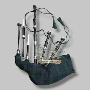 Puede incluir: Una gaita negra con detalles plateados y una bolsa de cuadros verdes y azules. La gaita tiene múltiples tubos de diferentes longitudes, con detalles blancos y negros. El texto "PIPERS & MASONS" es visible en la bolsa.