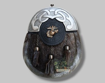 May include: A traditional Scottish sporran with a silver-toned cantle featuring a Celtic knot design. The sporran has a fur body, a black leather flap with a brass emblem, and three decorative tassels. The bottom of the sporran has a small label that reads "PIPERS & MASONS."