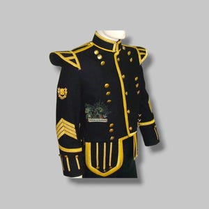 Pode incluir: Casaco militar preto com detalhes dourados, incluindo acabamentos, botões e ombreiras. O casaco apresenta bordados dourados nas mangas e no peito, e um emblema decorativo. O casaco é exibido em um manequim.
