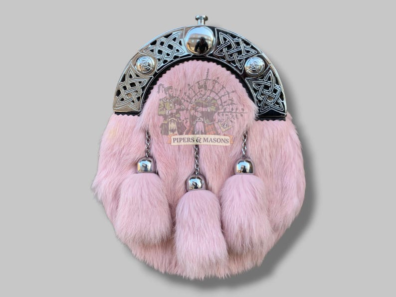 May include: Pink fur sporran with a silver Celtic design on the top and three matching tassels. The sporran has a silver clasp and chain. The text "PIPERS & MASONS" is printed on the front.