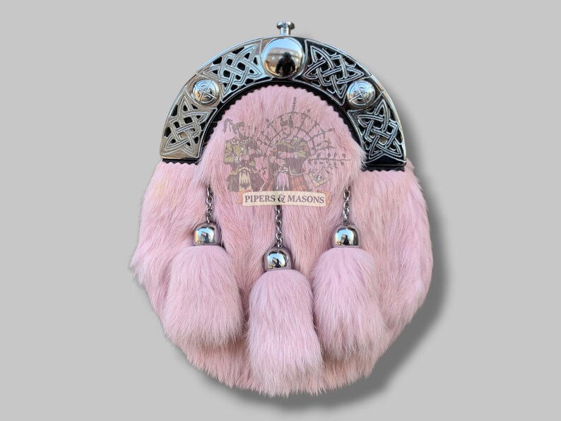 May include: Pink fur sporran with a silver Celtic design on the top and three matching tassels. The sporran has a silver clasp and chain. The text "PIPERS & MASONS" is visible on the front.