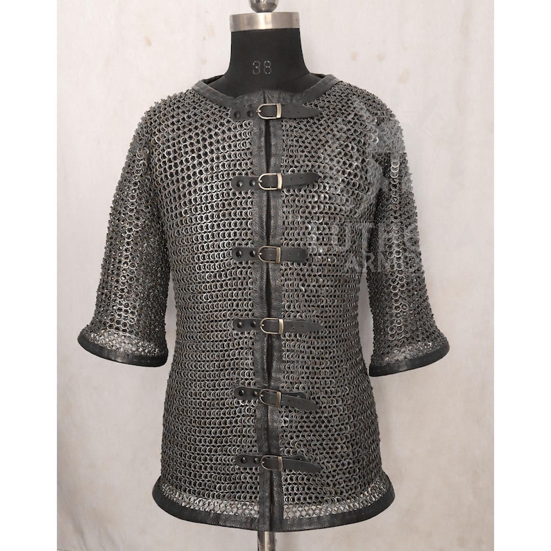 May include: A silver chainmail shirt with short sleeves and a leather collar and trim. The shirt has leather straps with buckles down the front. The sleeves end in a flared shape.