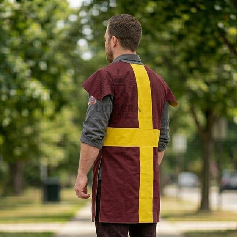 Pode incluir: Uma t&uacute;nica bord&ocirc; com um design de cruz amarela. A t&uacute;nica tem mangas curtas e uma bainha dividida. O texto "LUTERA SHOP" &eacute; vis&iacute;vel na parte superior das costas. A pessoa est&aacute; usando uma camisa cinza de manga comprida por baixo.