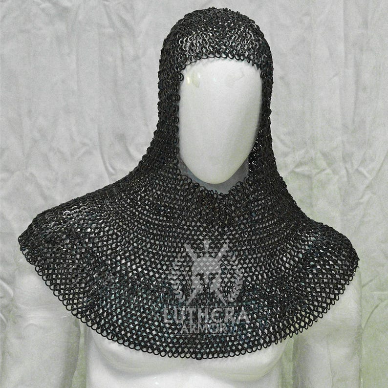 May include: A black chainmail coif, a medieval head covering, displayed on a mannequin. The coif covers the head and shoulders, constructed of small, interlocking metal rings. The coif is designed to protect the wearer's head and neck.