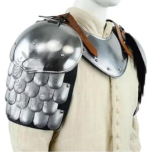May include: A silver-colored shoulder armor piece with a layered design. The armor has a rounded top and a series of overlapping, scale-like plates. Brown leather straps secure the armor. The armor is designed to protect the shoulder.