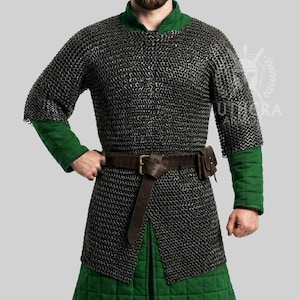 Könnte beinhalten: Ein mittelalterliches Kettenhemd mit grünen Akzenten. Das Hemd hat ein Metall-Kettenmuster über grünen Stoffärmeln und einem grünen Kragen. Ein brauner Ledergürtel mit einer Tasche wird um die Taille getragen.