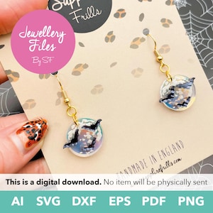 May include: A pair of gold-colored dangle earrings. Each earring features a round, iridescent charm with black bat silhouettes. The earrings are attached to a card with the text "Jewellery Files By SF" and "Supp Frills". The bottom of the card reads "This is a digital download."