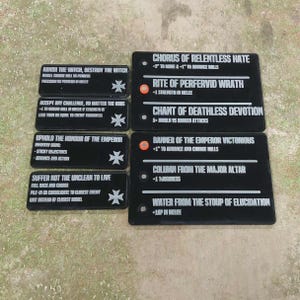Peut inclure: Jetons de jeu rectangulaires noirs avec du texte blanc et un symbole de croix. Les jetons comportent diverses phrases telles que "Abhor the Witch, Destroy the Witch" et "Chorus of Relentless Hate". Ces jetons sont pour un jeu de société.