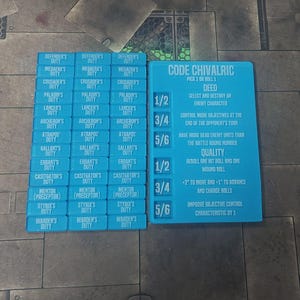May include: Two stacks of blue game cards with white text. One stack has the text "Defender's Duty" and other game terms. The other stack has the text "Code Chivalric" and game instructions. The cards are on a patterned surface.