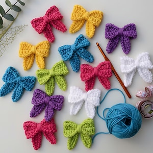 Puede incluir: Una colección de lazos de ganchillo hechos a mano en varios colores: rosa, amarillo, azul, verde, morado y blanco. Un ganchillo, una madeja de hilo azul y una cinta métrica sugieren un tema artesanal.