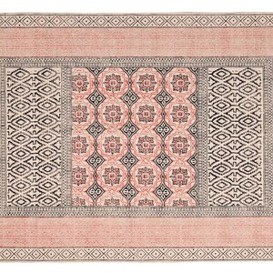 May include: A rectangular rug with a geometric design. The rug features a pink border with a diamond pattern and fringe on the short ends. The center has a repeating pattern of black and pink shapes.