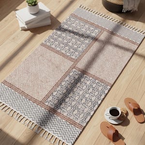 Può includere: Un tappeto rettangolare con design patchwork caratterizzato da blocchi alternati di motivi floreali blu ardesia e complessi motivi circolari beige. Il tappeto è bordato da un motivo a zigzag marrone e rifinito con frange color crema.