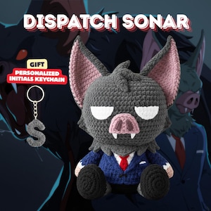 May include: A crocheted bat plush toy with a blue suit and red tie, white eyes, and a pink nose and ears. A personalized initial keychain with the letter "S" hangs to the left. The text "DISPATCH SONAR" is at the top.