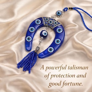 May include: A blue horseshoe-shaped amulet with multiple eye-shaped charms and a blue tassel. The amulet is suspended by a blue cord and rests on a satin surface. The text on the image reads: "A powerful talisman of protection and good fortune."