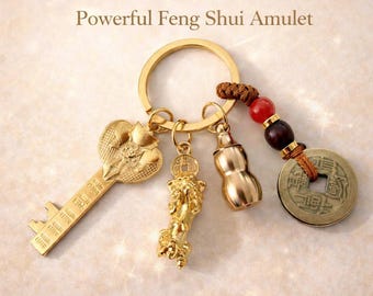 May include: A gold-toned keychain featuring a key charm, a mythical creature charm, a gourd-shaped charm, and a round coin charm with a red and dark brown bead. The text reads: Attract Wealth & Good Fortune Powerful Feng Shui Amulet Ready to Gift Limited Edition.
