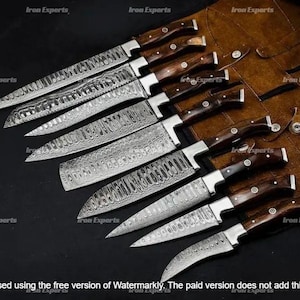 May include: A collection of Damascus steel knives with wooden handles. The blades feature a distinctive patterned design. The knives are displayed on a brown leather sheath, with the text "Iron Experts" visible.