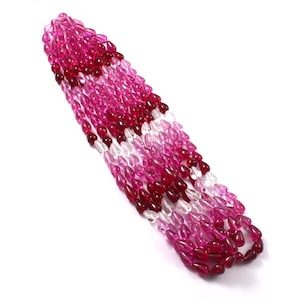 May include: A collection of teardrop-shaped beads arranged in a vertical cluster. The beads feature a gradient of translucent colors, ranging from deep magenta and dark red to lighter pink and clear, colorless glass-like tones throughout.