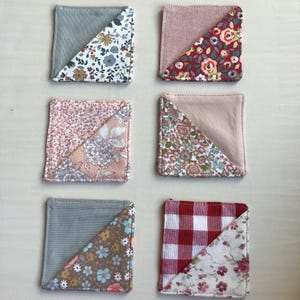 Puede incluir: Seis posavasos cuadrados de tela. Cada posavasos está dividido diagonalmente, con una mitad de color sólido y la otra mitad con un diseño floral o estampado. Los colores incluyen gris, rosa, rojo y blanco. Los posavasos son probablemente para la decoración del hogar.