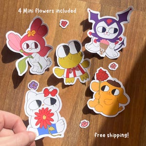 Puede incluir: Un conjunto de pegatinas de personajes de dibujos animados, incluyendo un conejo, una rana, un gato y un perro, cada uno con una flor. Las pegatinas son coloridas, con el texto "4 mini flores incluidas" y "¡envío gratis!" visible.