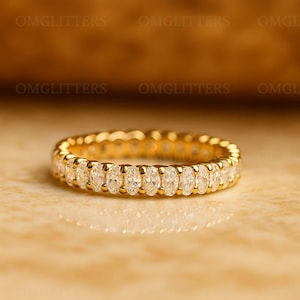 Peut inclure: Une bague d'éternité en or avec une rangée continue de diamants de taille ovale. La monture de la bague est également en or, créant un design élégant. Les diamants scintillent, reflétant la lumière. La bague est un symbole d'engagement et d'amour.